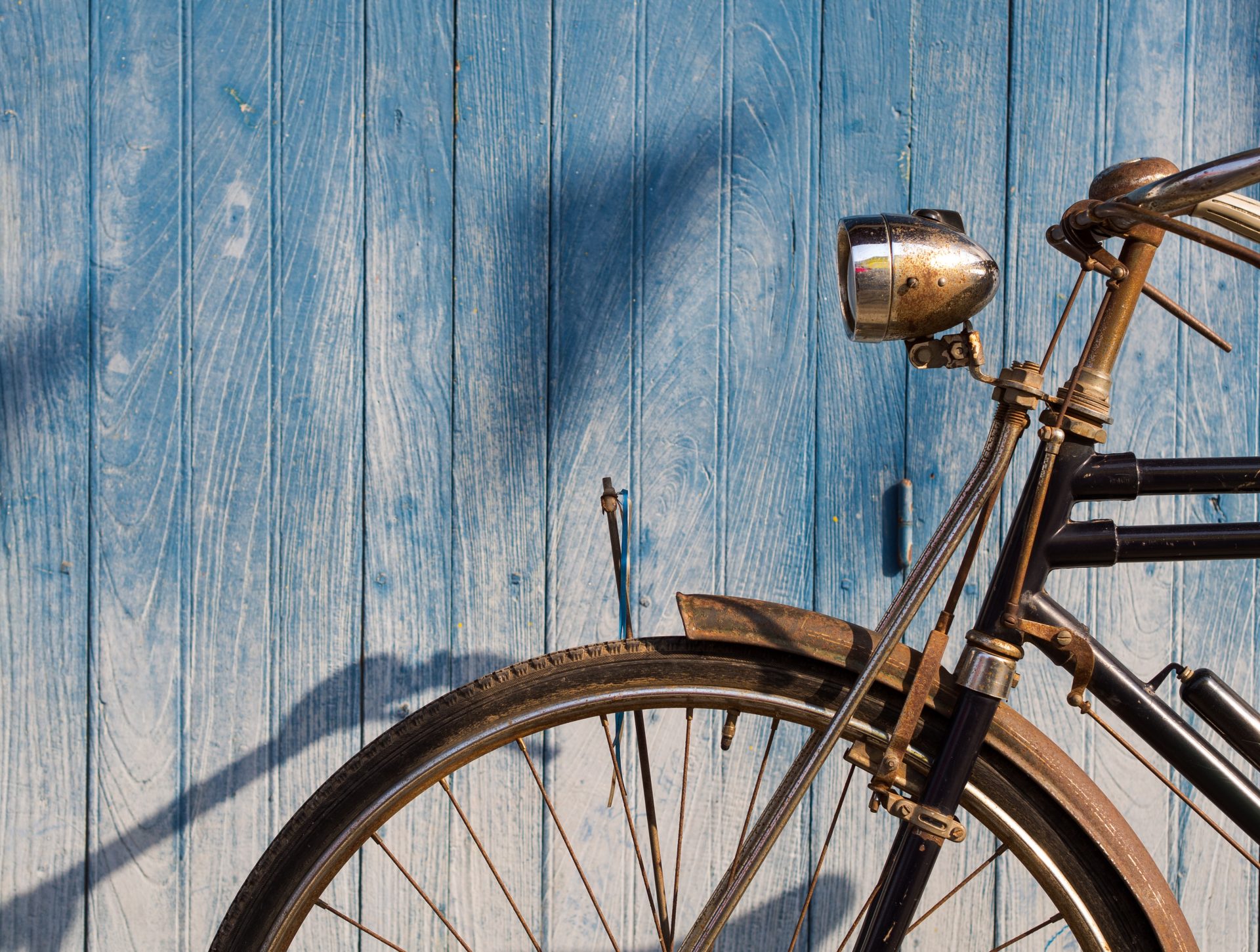 Old bicycle parked in front of blue plank floor for text and background.